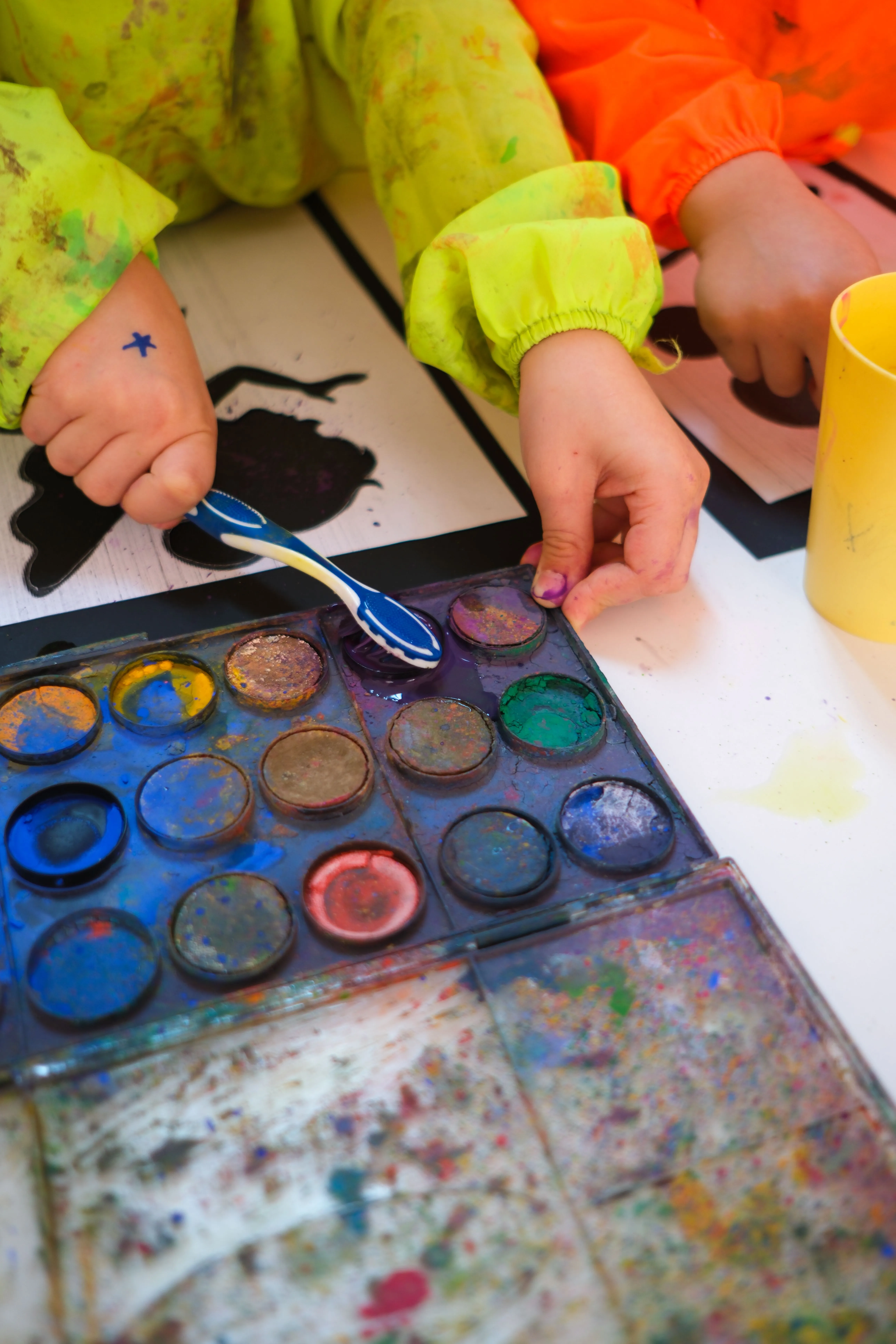 Mains d'un enfant manipulant de la peinture colorée lors d'un accompagnement thérapeutique